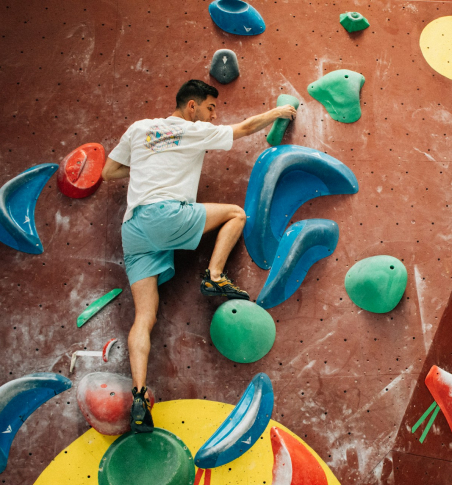 a man attempting a bouldering problem at an indoor gym